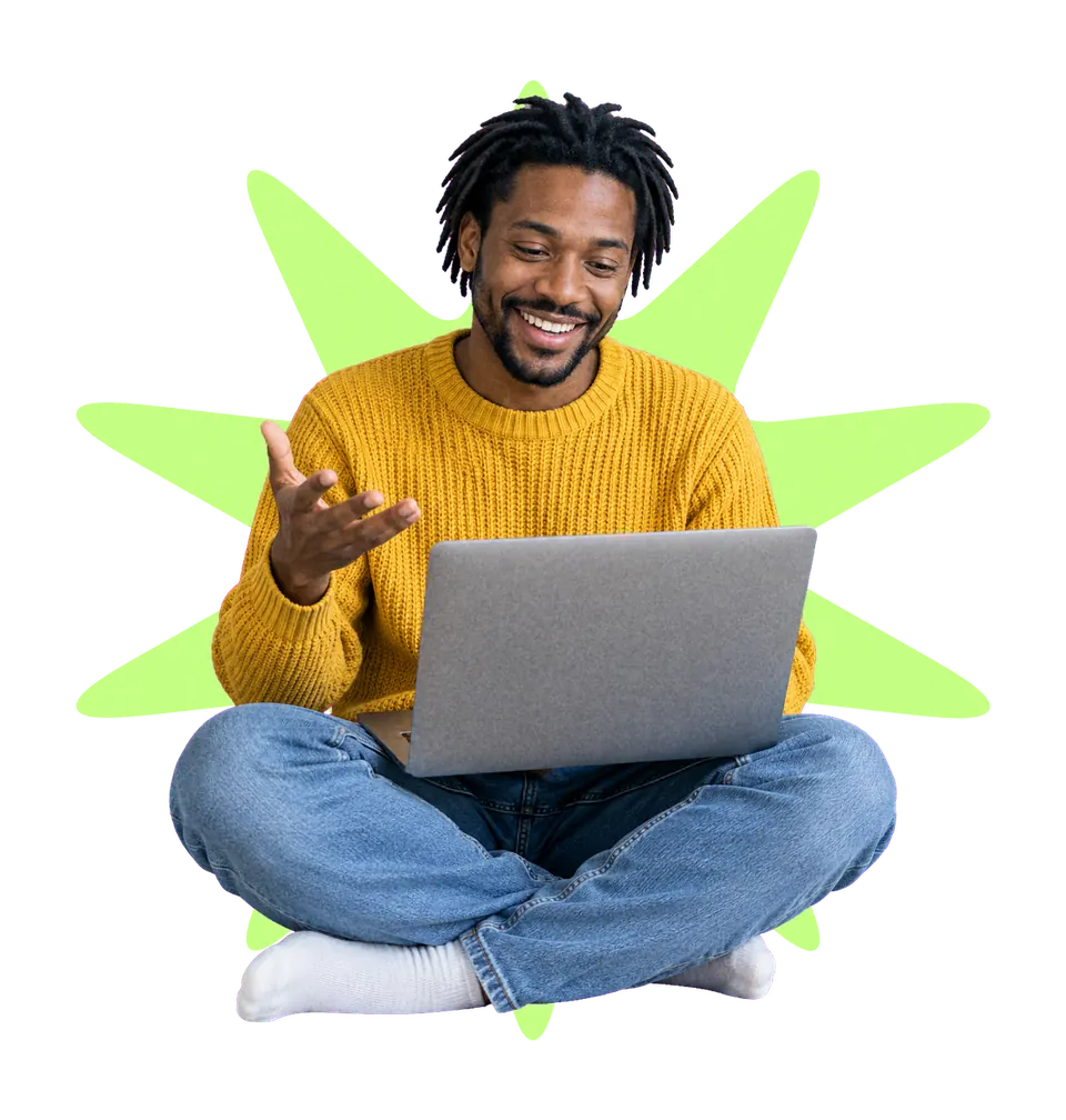 A smiling man sitting cross-legged with a laptop on his knees, cut out over a lime and gold starburst